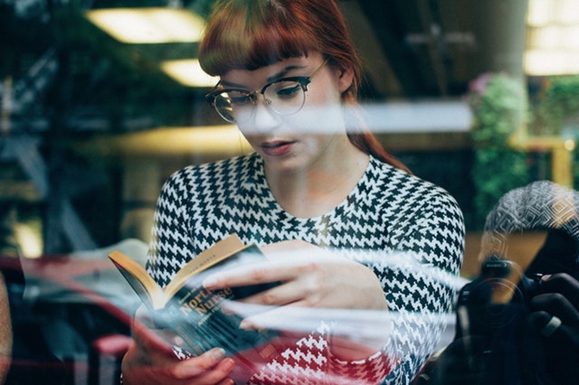 Žena čítajúca knihu za sklenenou stenou.jpg